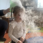 Przedszkolak siedzący na krzesełku z głową w chmurze z suchego lodu