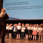 Dzieci śpiewają na scenie przy akompaniamencie pianina