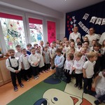 Dzieci z nauczycielkami na tle dekoracji z okazji Święta